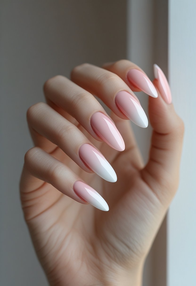 A close-up of a woman's hand showing nails with a soft pink to white gradient manicure.